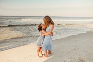People enjoying a playful moment together on a sandy beach at sunset.