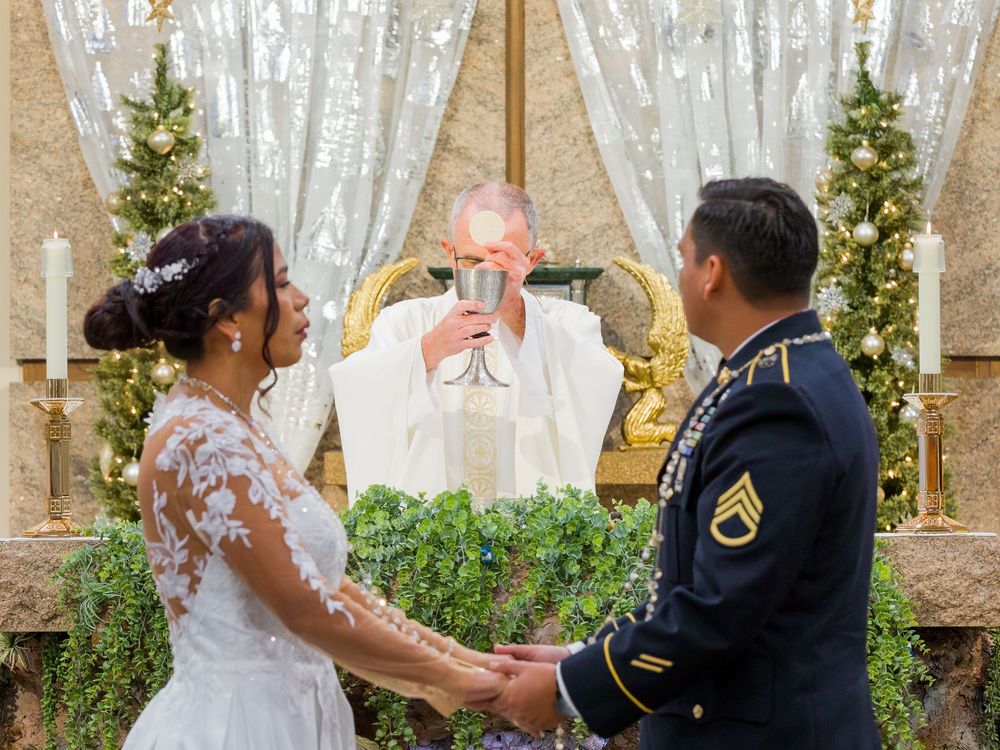 A wedding couple shares their first dance in front of elegant white curtains and greenery at an indoor venue.