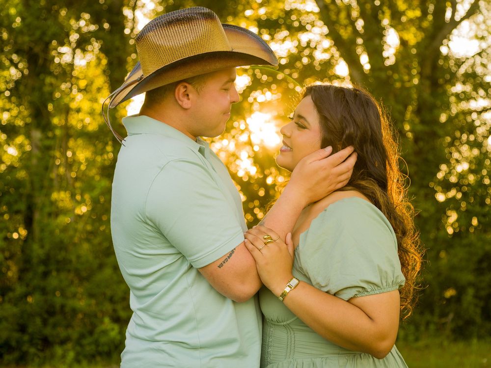 A couple in matching mint green shirts share an intimate moment at sunset in a wooded setting.