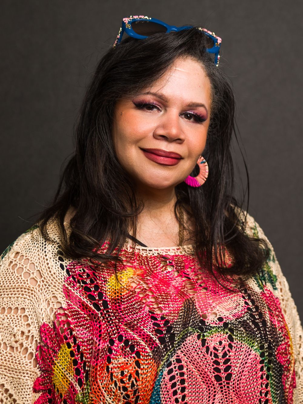Portrait series of a woman in colorful crochet attire with bright accessories against dark background.