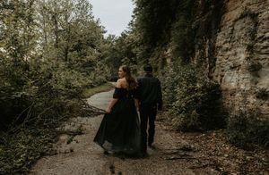 Couple walking together on path beside towering rock wall.