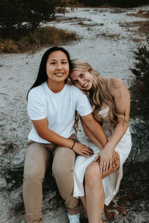Casual outdoor portrait session with couple in white shirts and khaki pants sitting together.