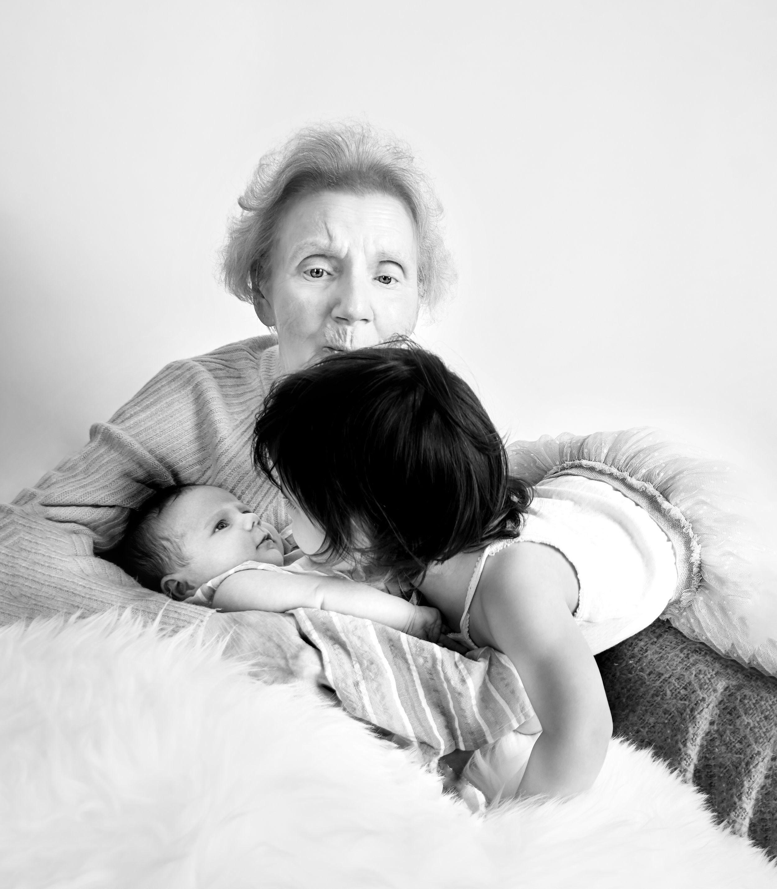 Scottish Great Grandmother kissing her granddaughters one newborn and one toddler