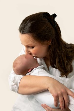 Mum kissing newborn son on the head as he is cradled in her arms