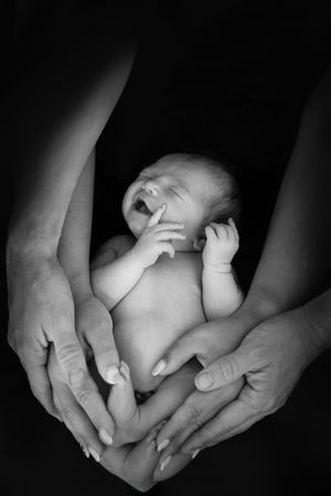 Gentle black and white photograph showing tiny baby feet cradled in caring hands.