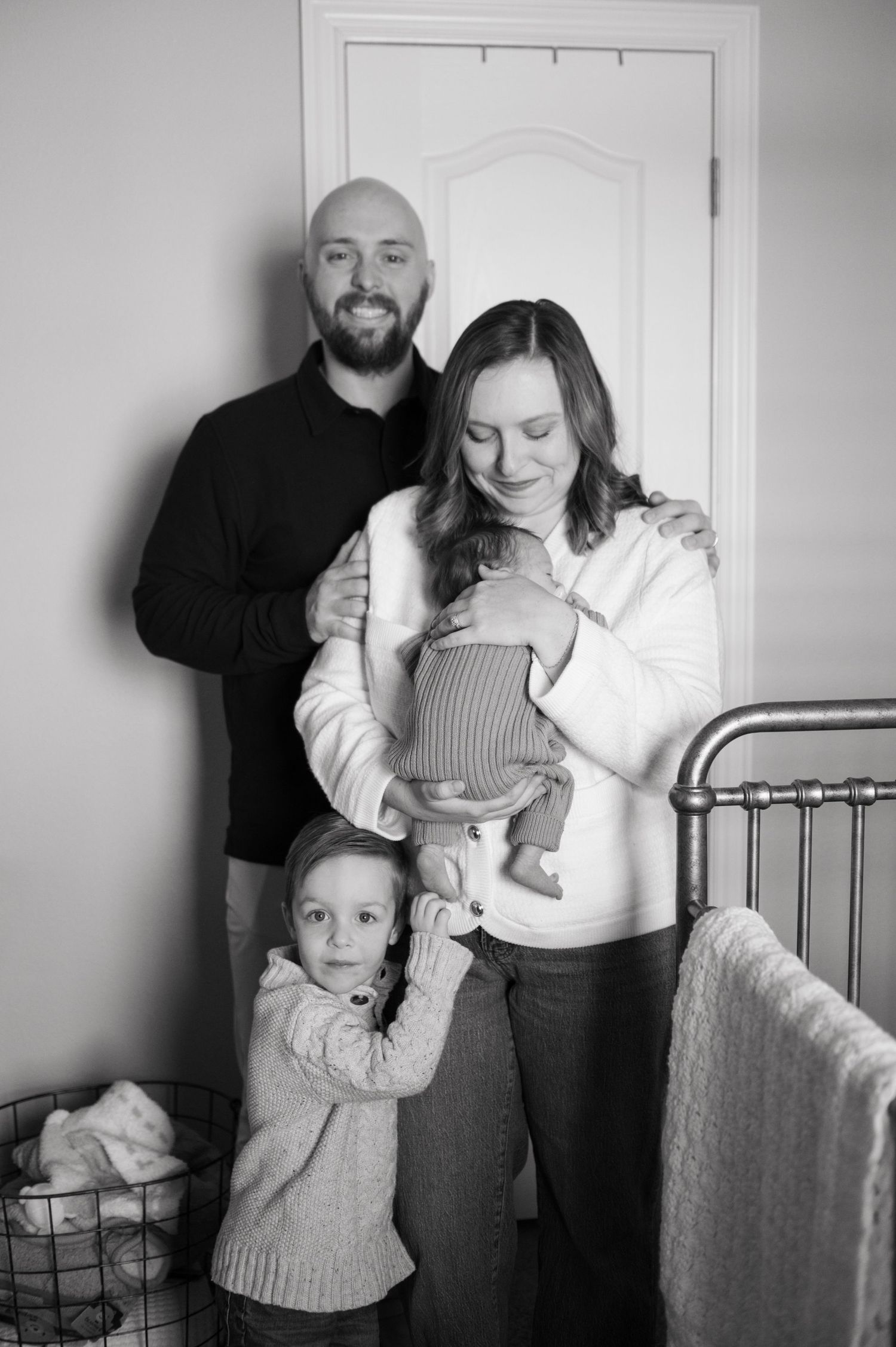 Newborn photos with mom, dad, and toddler in the Grapevine Botantical garden. Mom holding belly and dad holding their toddler.