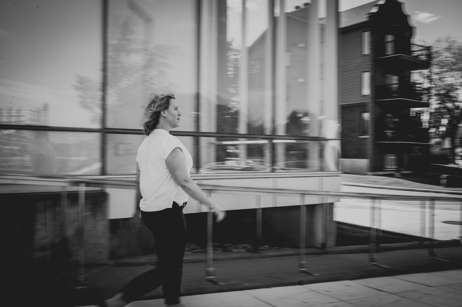 Black and white photo of someone looking through reflective glass windows.