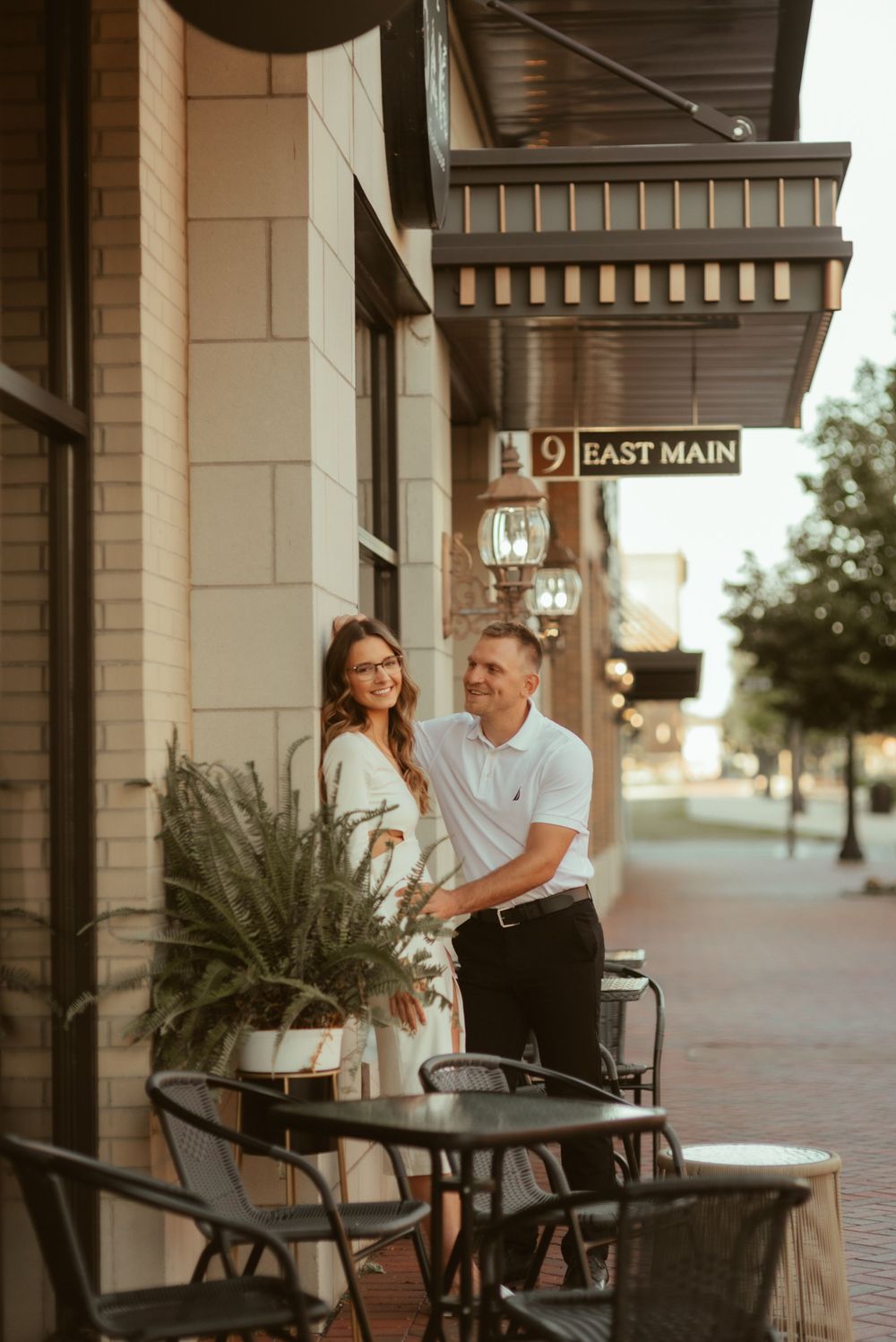 A couple poses together on a cafe patio during golden hour on East Main street.