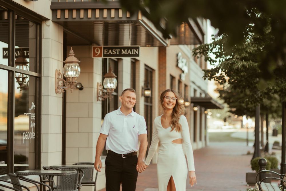 A couple walks hand in hand along East Main street in formal attire during sunset.