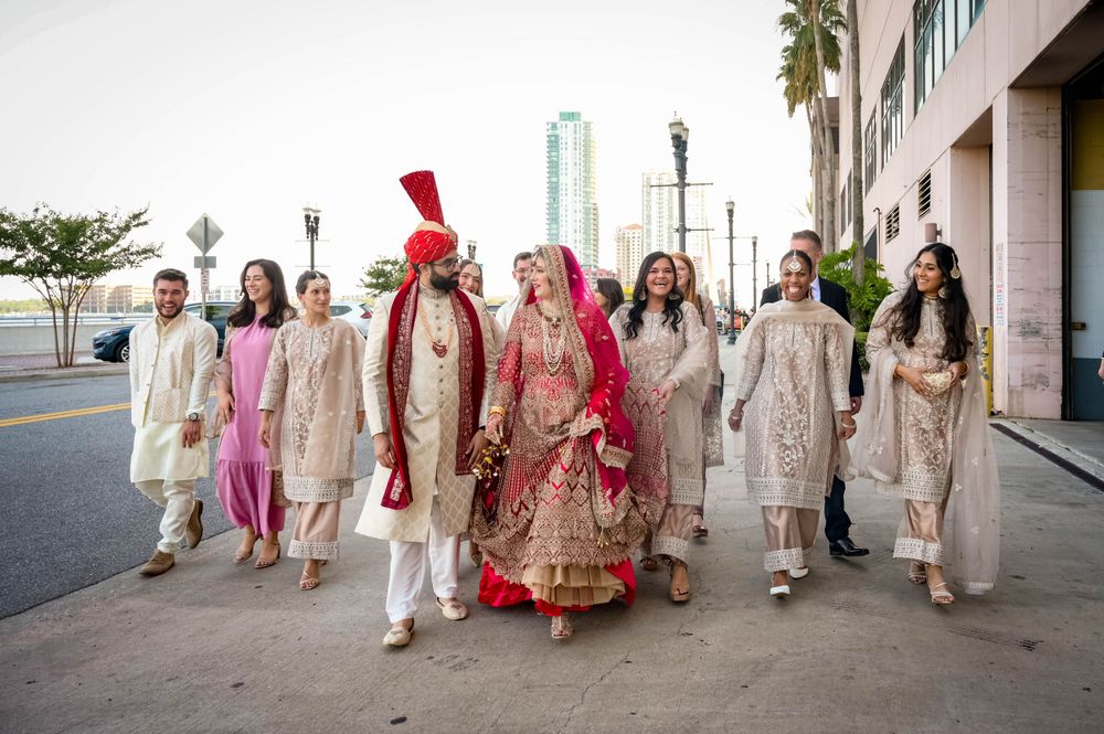 Couple in traditional South Asian wedding attire sharing intimate moment against urban backdrop.