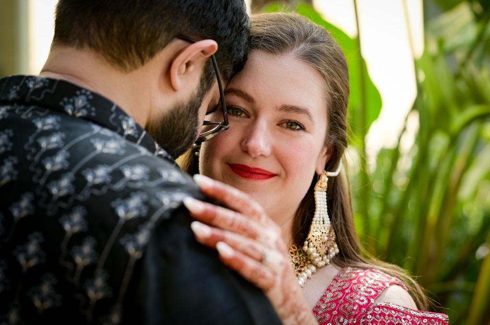 Intimate moment between couple in traditional Indian wedding attire with decorative jewelry.