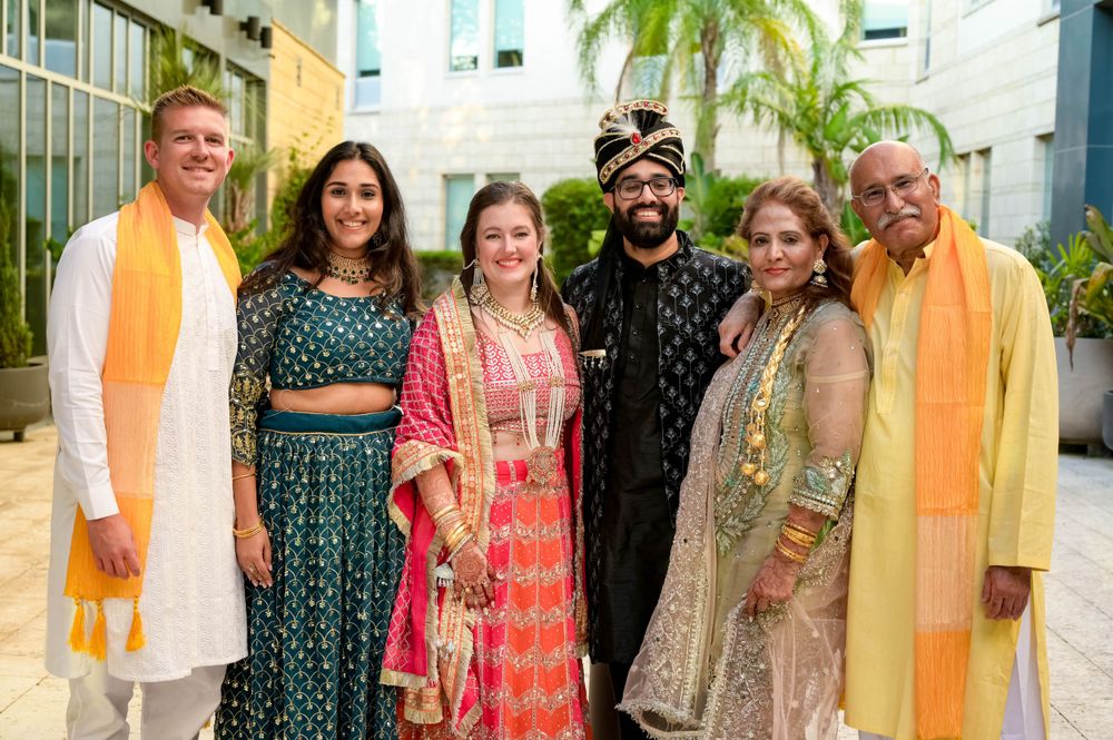 Wedding group wearing mix of traditional Indian outfits posing together in courtyard.