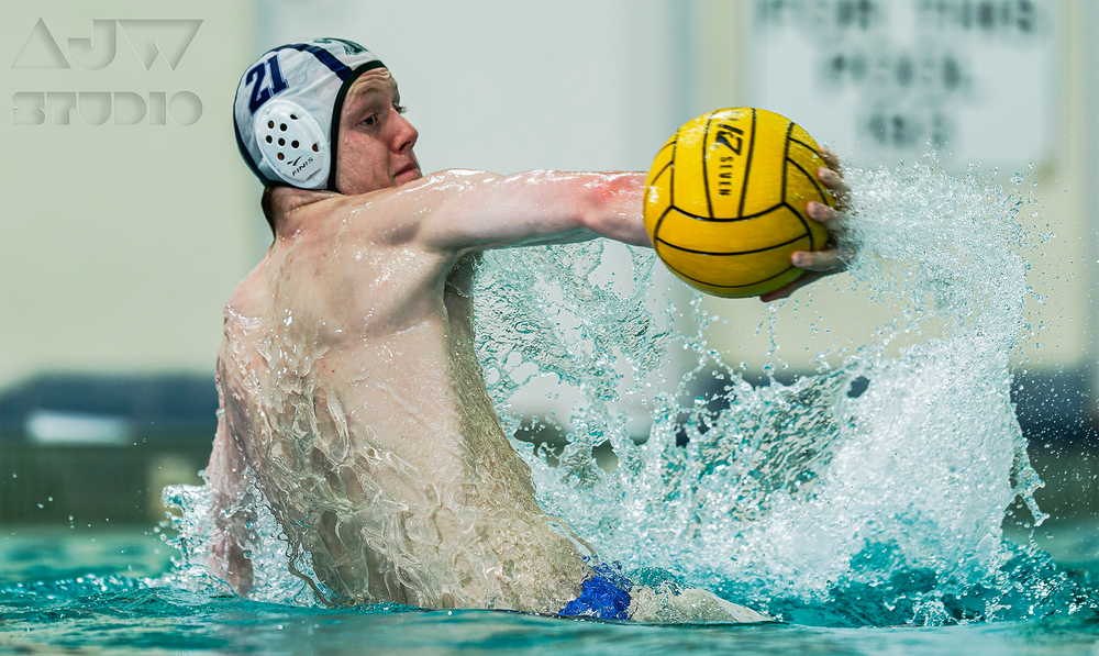 A water polo player in a white cap prepares to throw the yellow ball.
