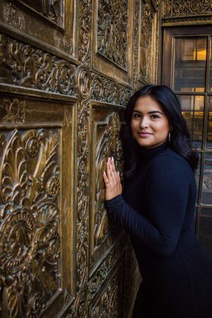 An artistic portrait against an ornate golden door with intricate carved details.