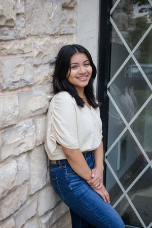 A casual portrait against a stone wall with rustic windows.