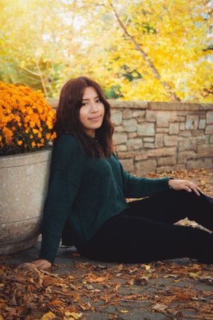 Autumn portrait session against stone wall with vibrant yellow foliage backdrop.