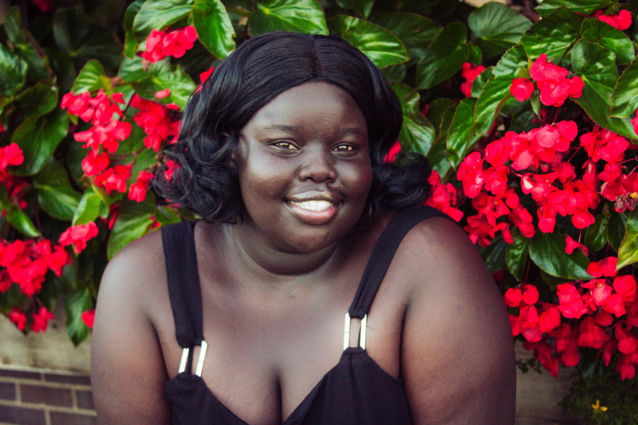 Portrait series against vibrant red flowers and green foliage in an outdoor garden setting.