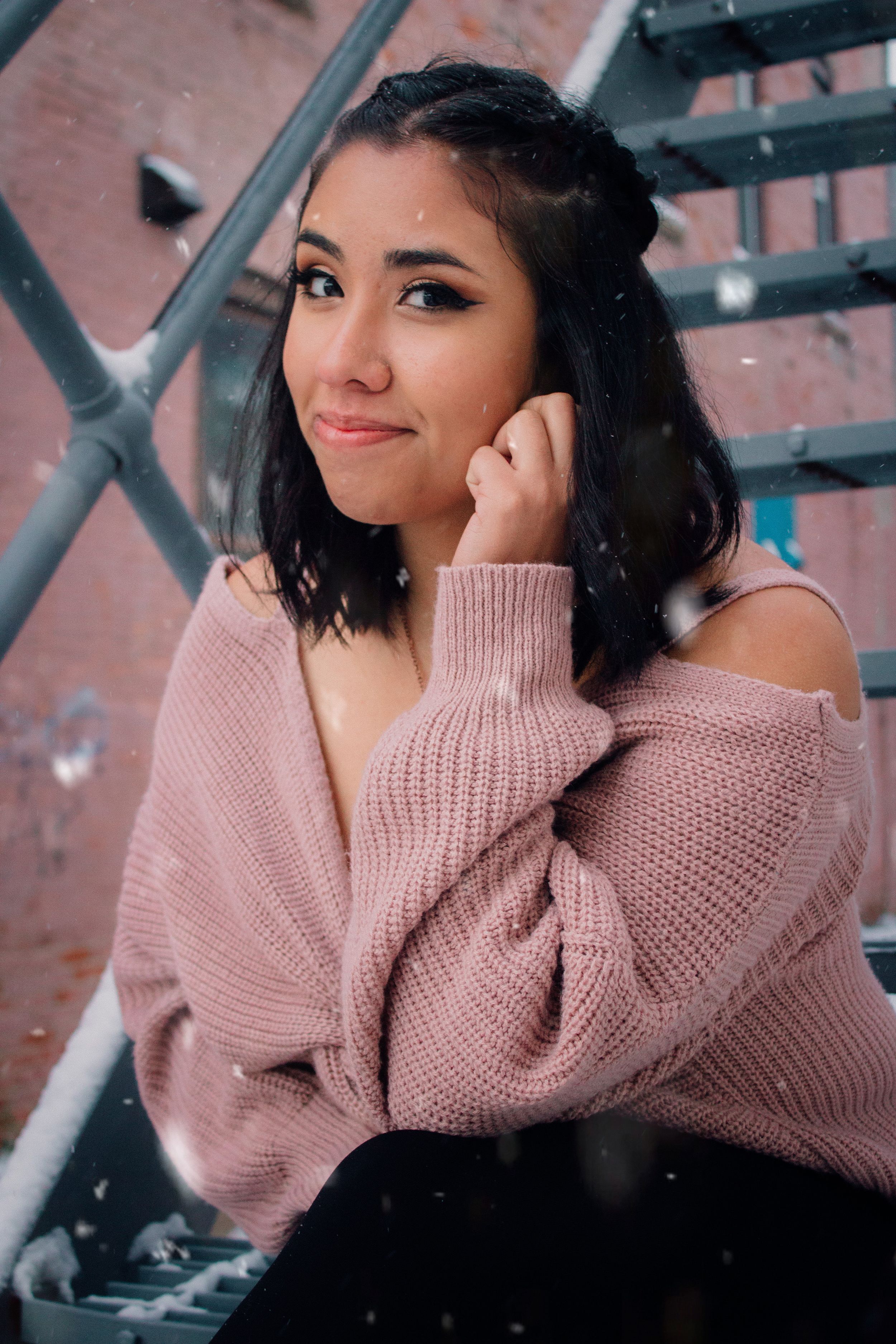 Portrait featuring soft pink sweater against industrial metal background.