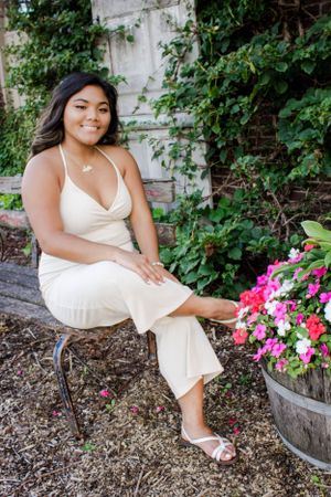 Elegant outdoor portraits in a white dress against ivy-covered wall and colorful flower garden.