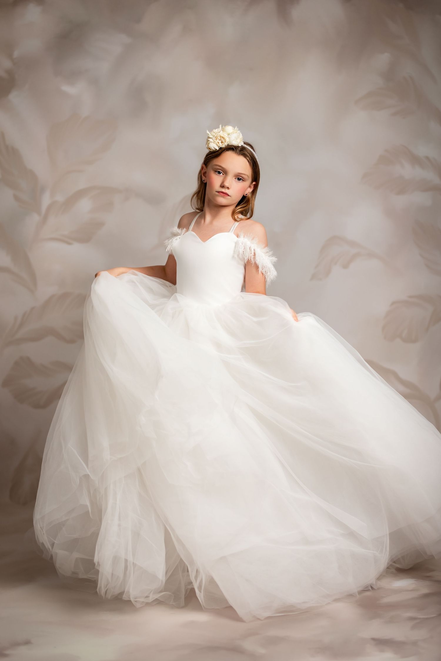An ethereal portrait featuring a flowing cream lace dress against a neutral studio background.