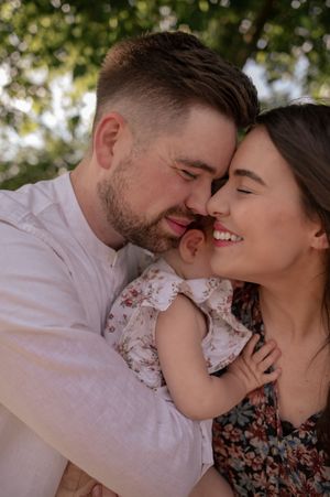 Parents hugging with they beautiful daughter in sunset