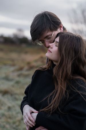 young couple day dreaming on the field while hugging each other in Irish winter