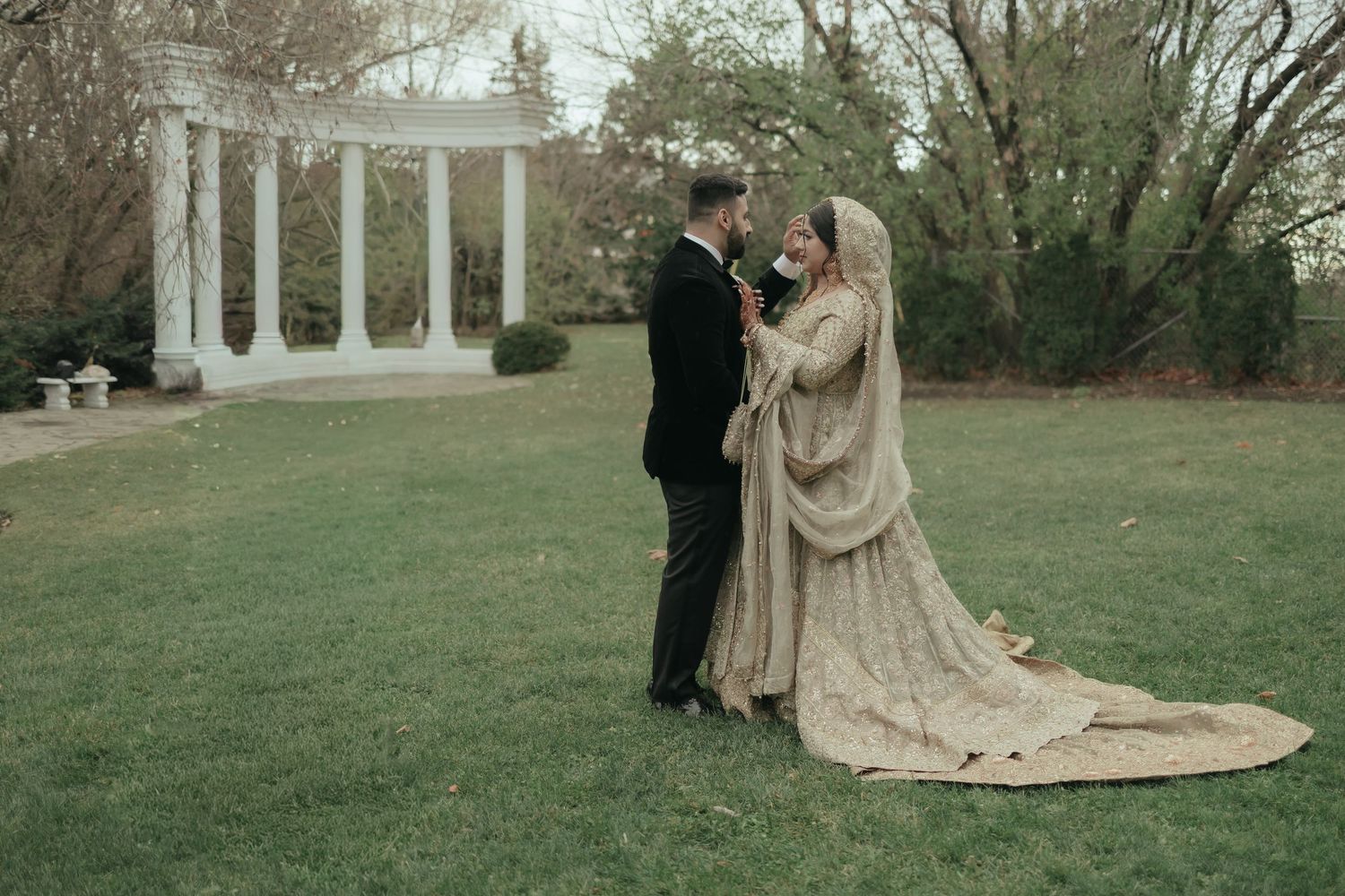 A happy couple shares a joyful laugh together on their wedding day, with the bride in white and groom in burgundy.