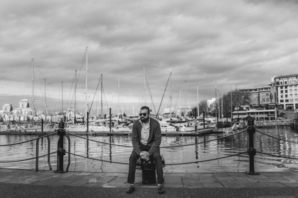 Peaceful black and white scene at a marina with boats docked and cloudy skies overhead.