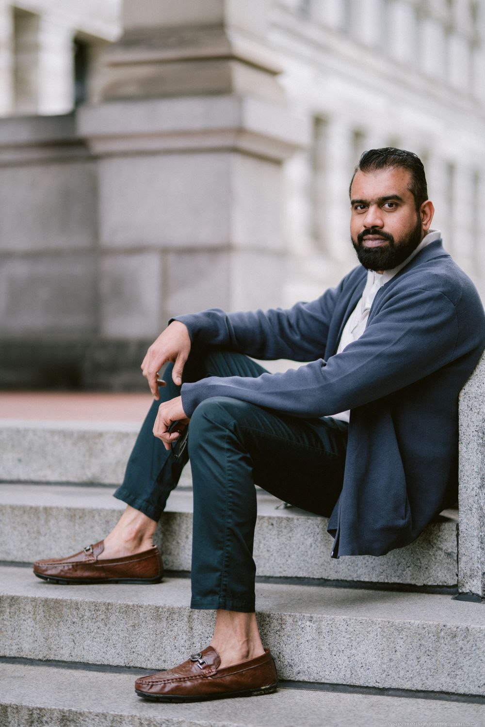 Professional casual style featuring loafers and cardigan on stone steps.