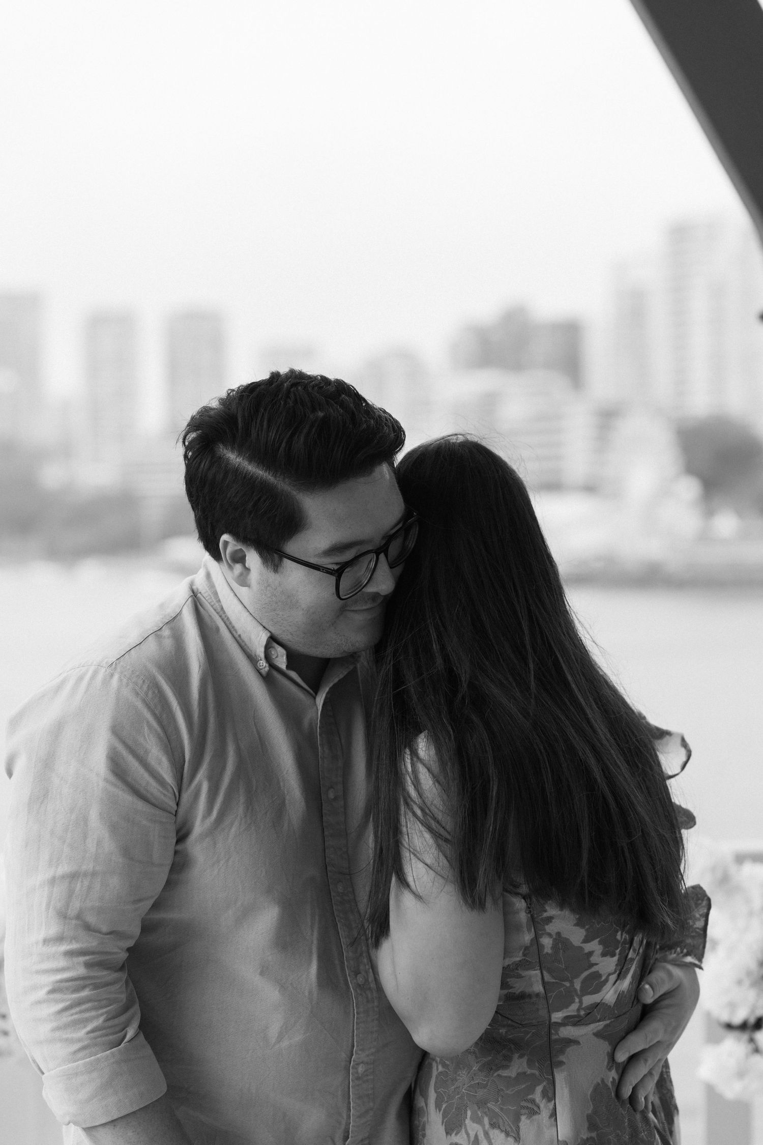 Romantic black and white cityscape portrait with tender moment on a balcony.