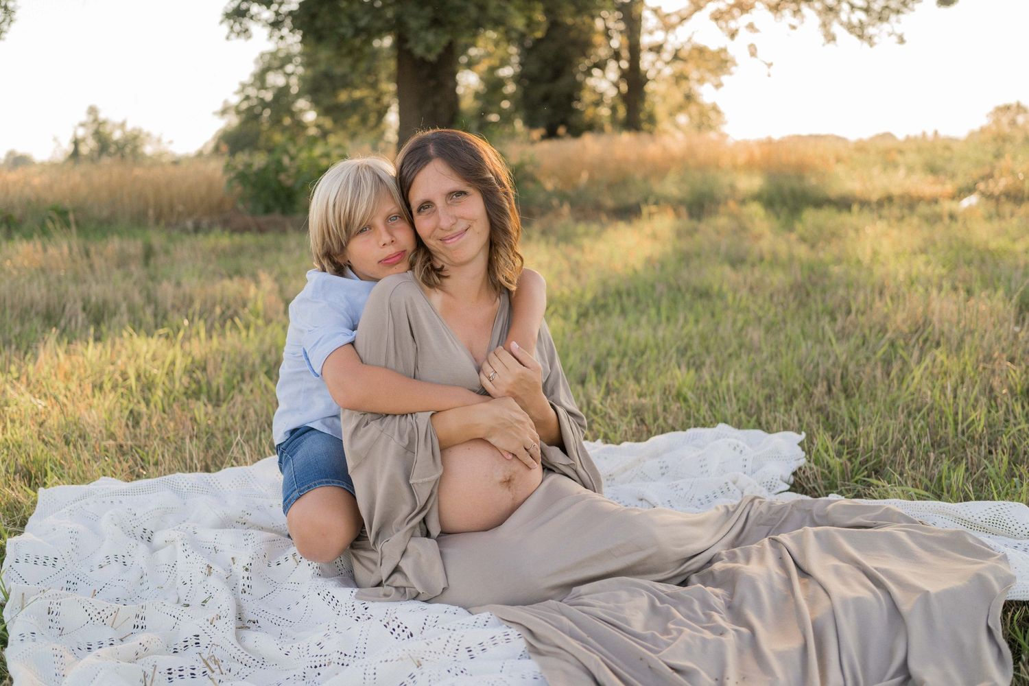 figlio maggiore con mamma incinta, fotografia di famiglia, campo, fotografia estiva al tramonto, famiglia campo verde, tramonto estate