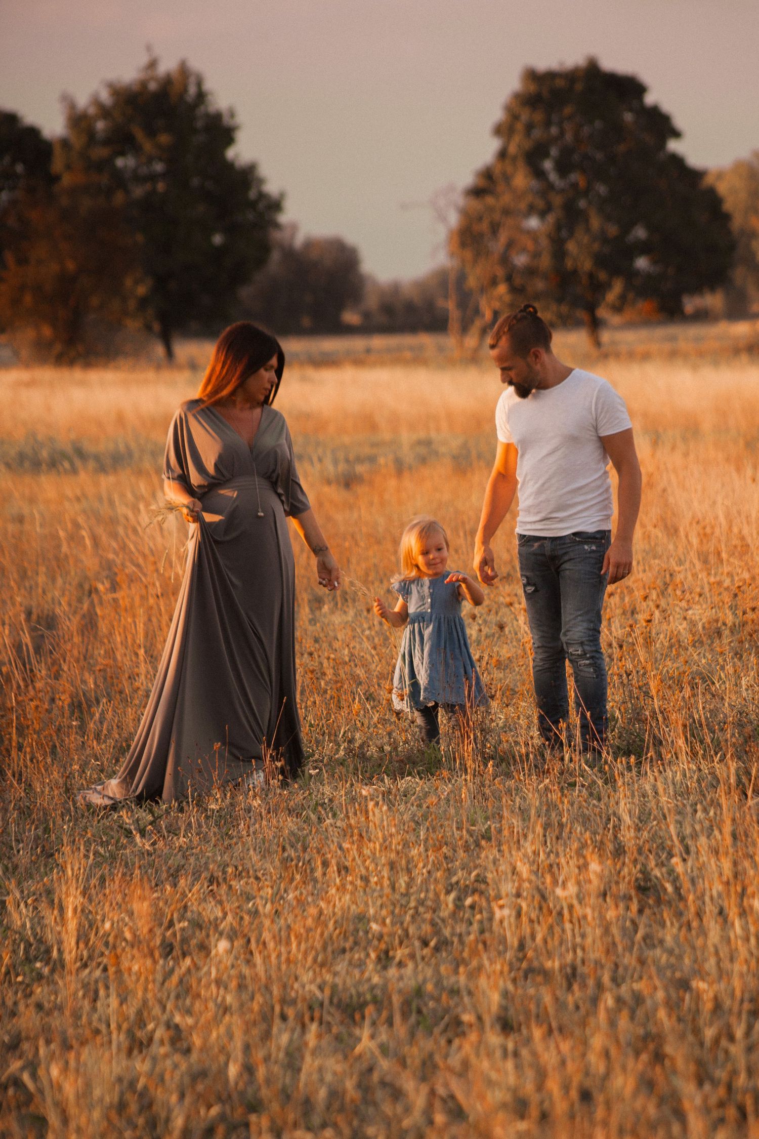 bimba tra mamma e papà, sessione fotografica in esterna a Peschiera Borromeo, sessione baby provincia Milano, campi, tramonto