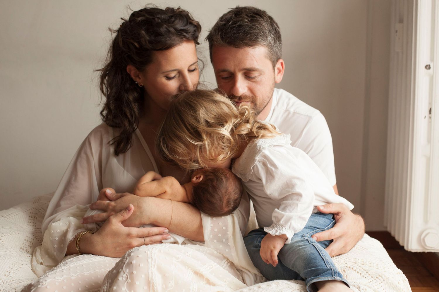 Mamma con suoi figli, una neonata con la sorella più grande, mani sul neonato, bimba bacia suo fratello neonato. Sessione family a Milano
