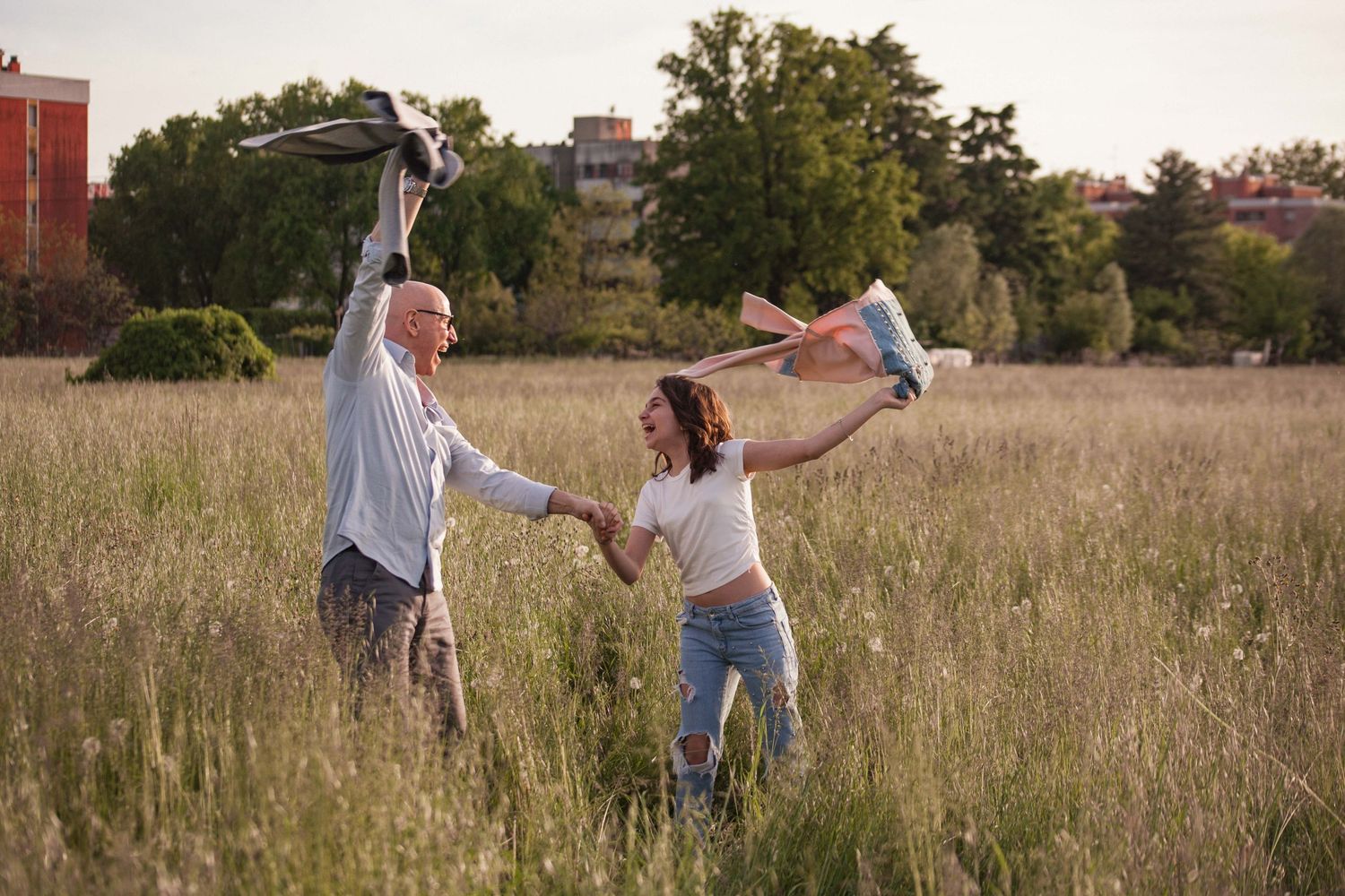 papà e figlia danzano ballano e ridono in un campo di fiori, erba a peschiera borromeo, fotografati da elisabetta massera photography