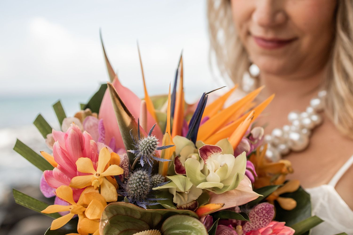 Close up of tropical bouquet and out of focus woman wearing pearl necklace on Maui