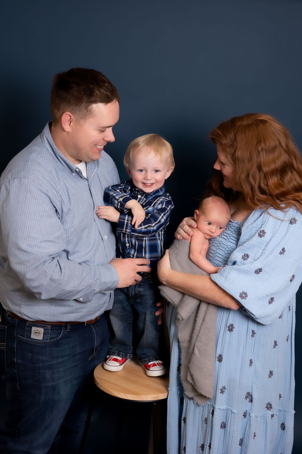 A family shares a tender moment together against a dark backdrop as they hold their children.