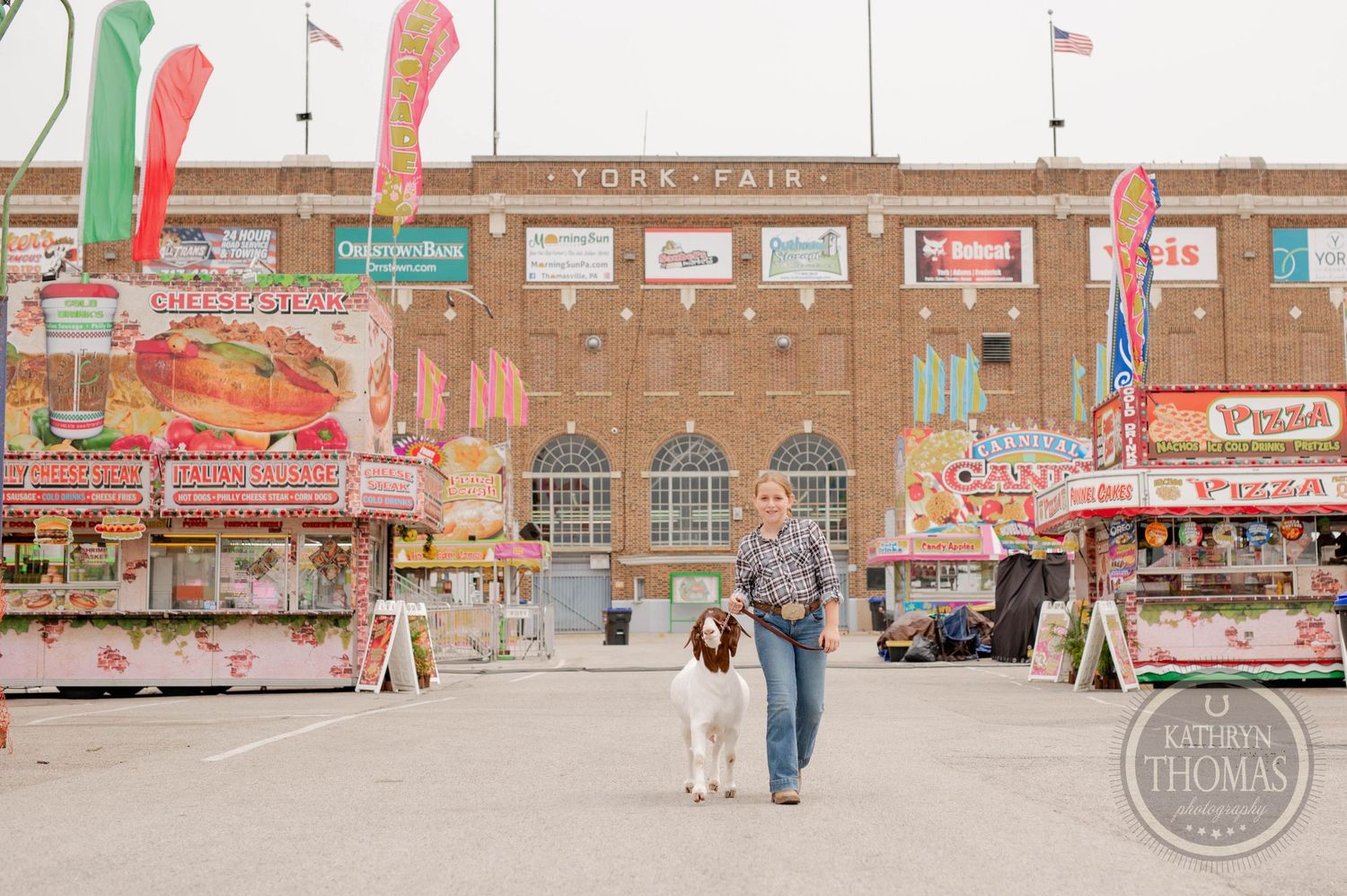 Fair vendor stalls and concession stands line the walkway at a county fair.