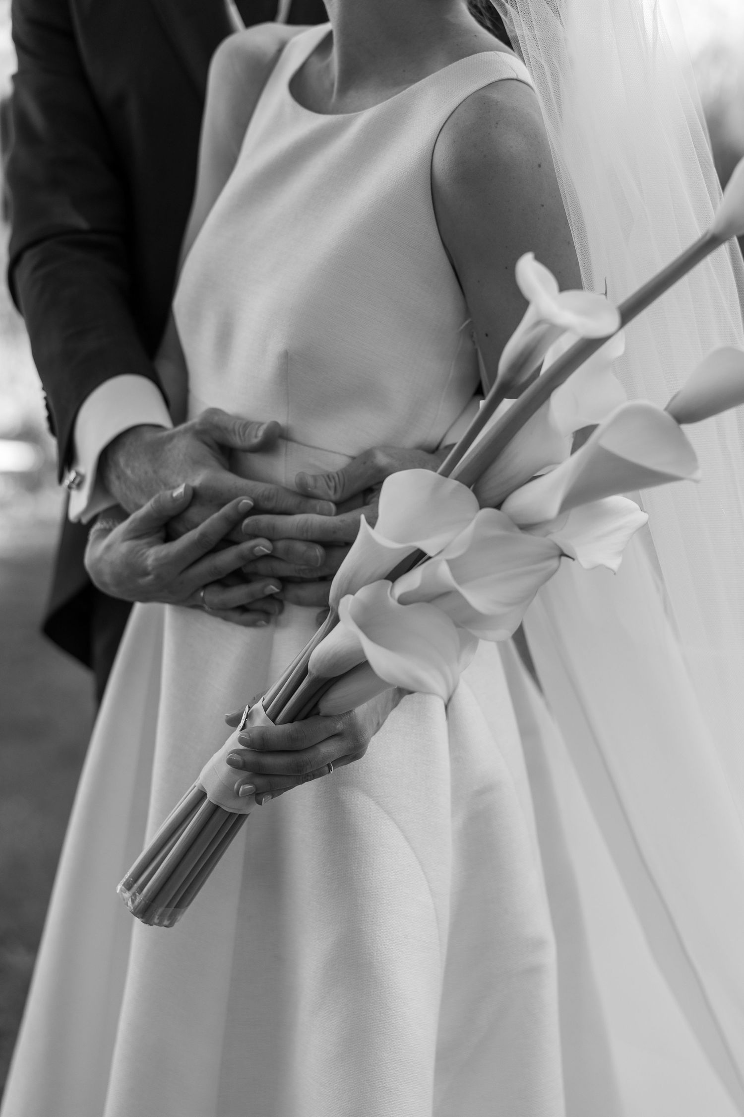 Row of bridesmaids in elegant white dresses holding bouquets during a formal wedding ceremony.