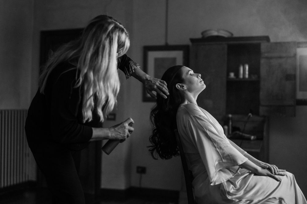 Black and white photo of a hair stylist working on a client's hair in preparation for a special occasion.