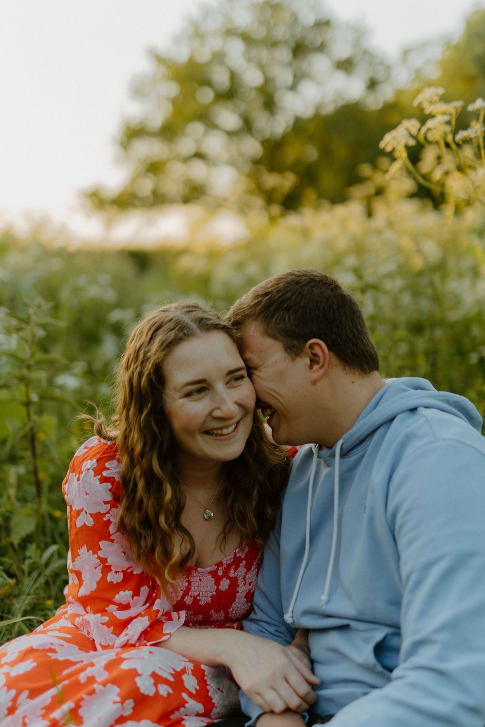 A couple shares an intimate moment while sitting in a field during golden hour.