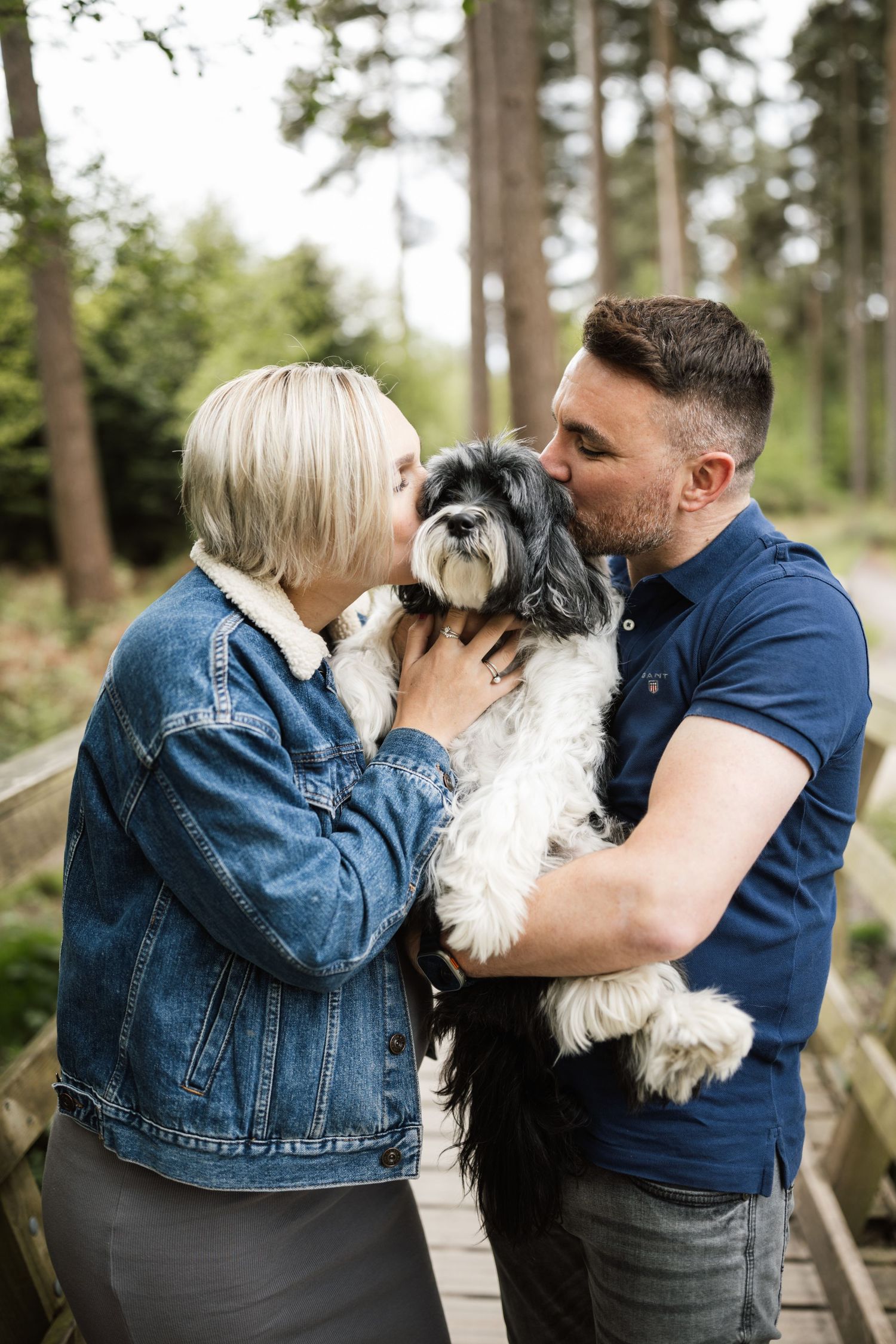 A couple shares affectionate moments with their small white and gray dog in a series of outdoor photos.