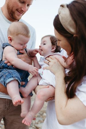 A series of candid family moments showing parents playing with and kissing a baby wearing denim overalls.