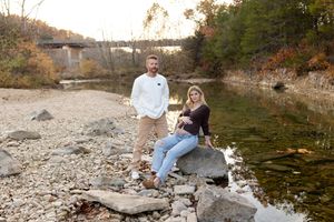 Natural outdoor engagement session by a rocky waterfront during autumn season.