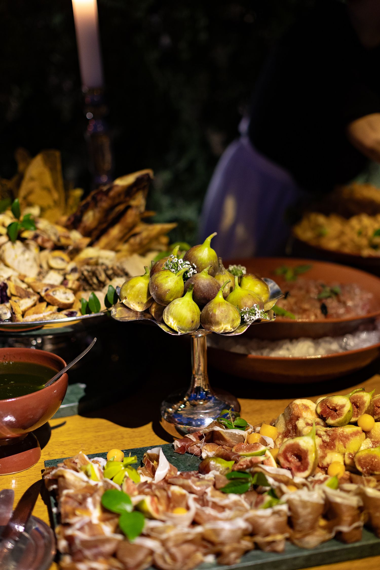 Artfully plated appetizers with fresh herbs and citrus garnishes arranged on rustic earthenware dishes at a catered event.