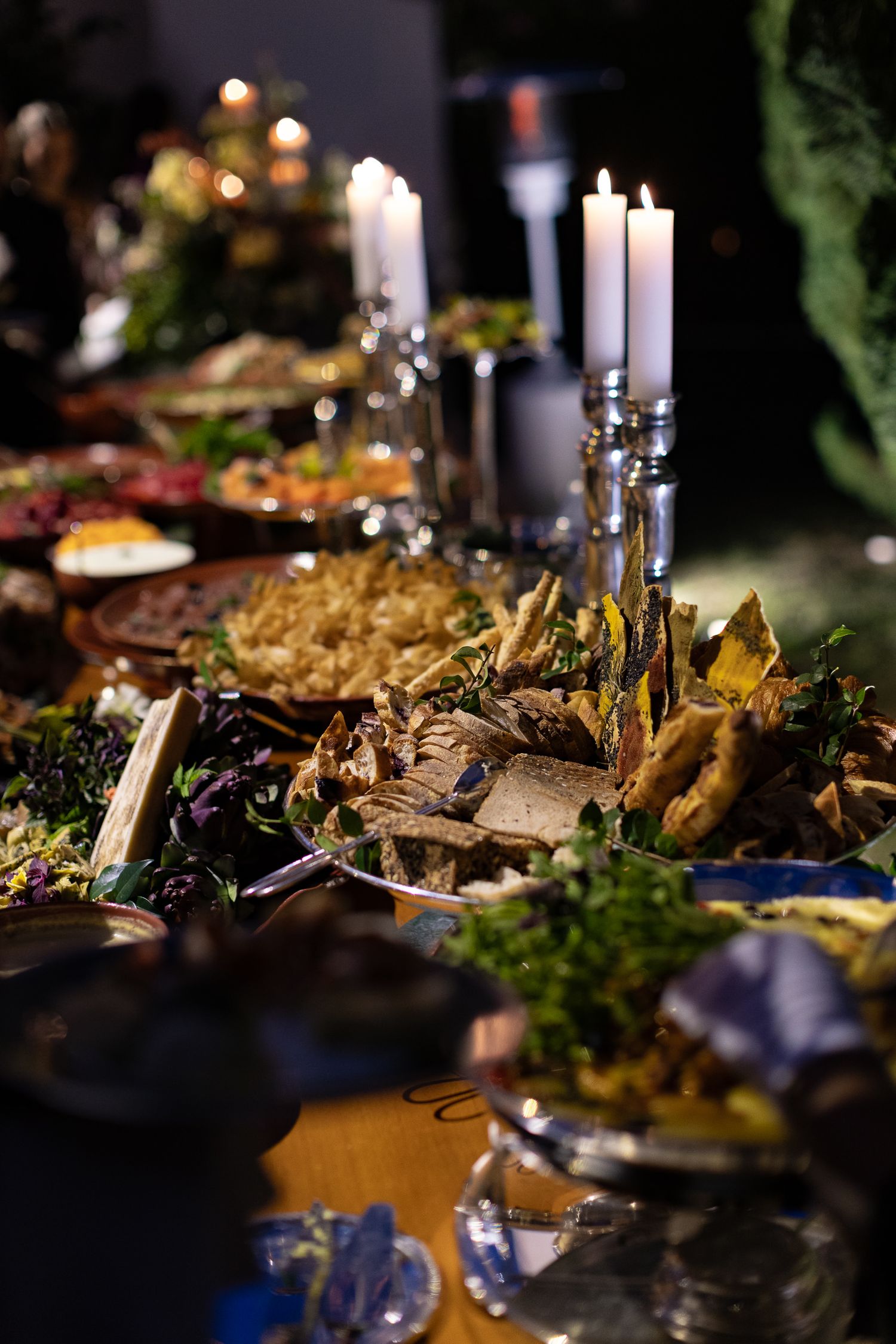 Elegant buffet table with candlelit dishes featuring roasted vegetables and gourmet entrees at an upscale dinner event.