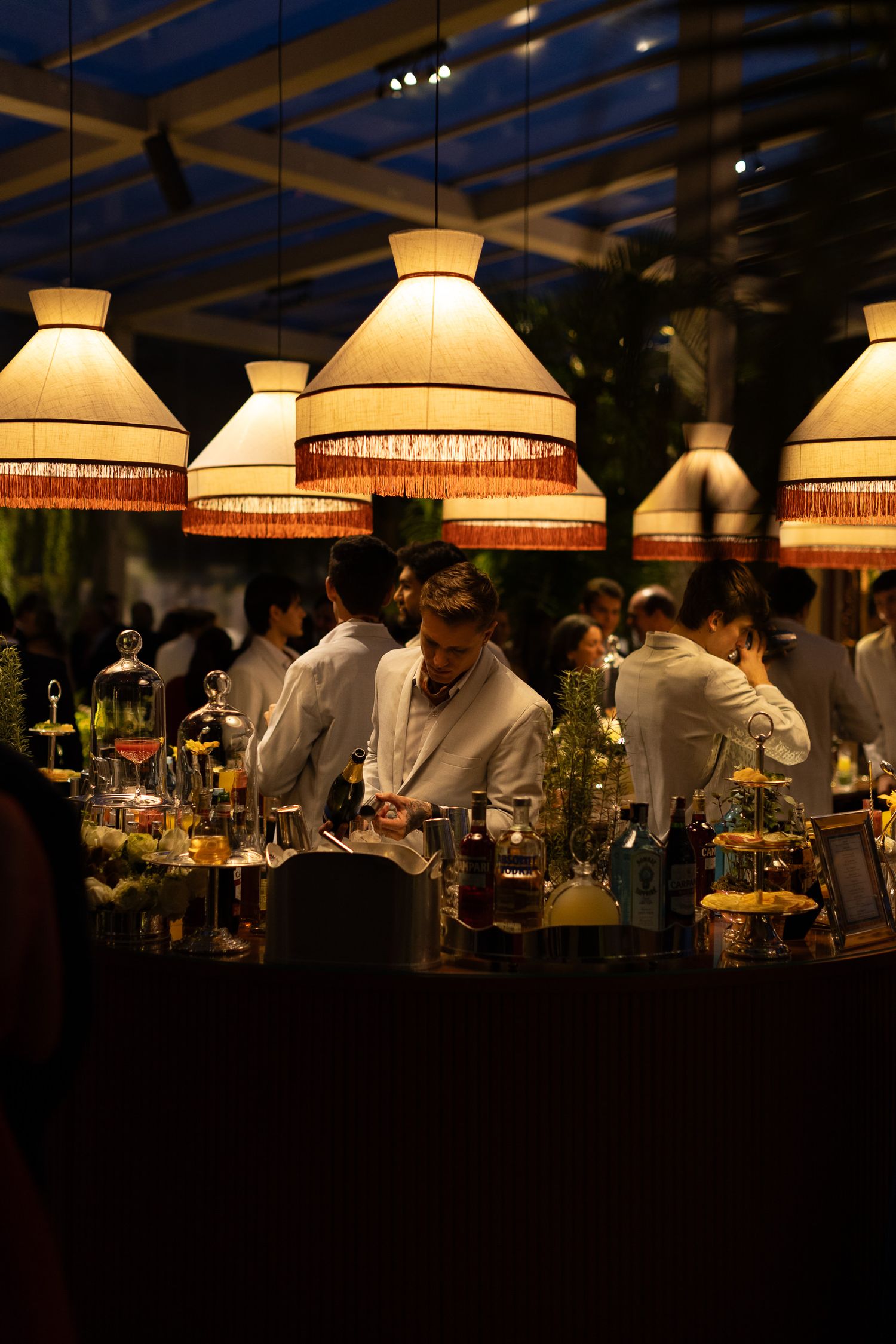 Dimly lit restaurant interior with warm glowing pendant lamps hanging above dining tables creating an intimate ambiance.