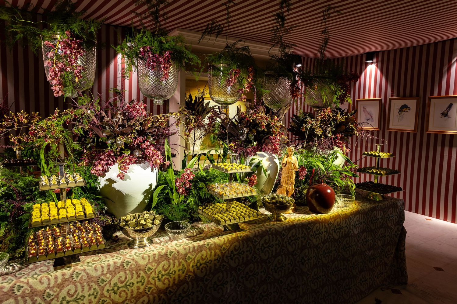 Beautifully lit garden display featuring lush plants, flowers and decorative elements in a striped-wall retail setting.