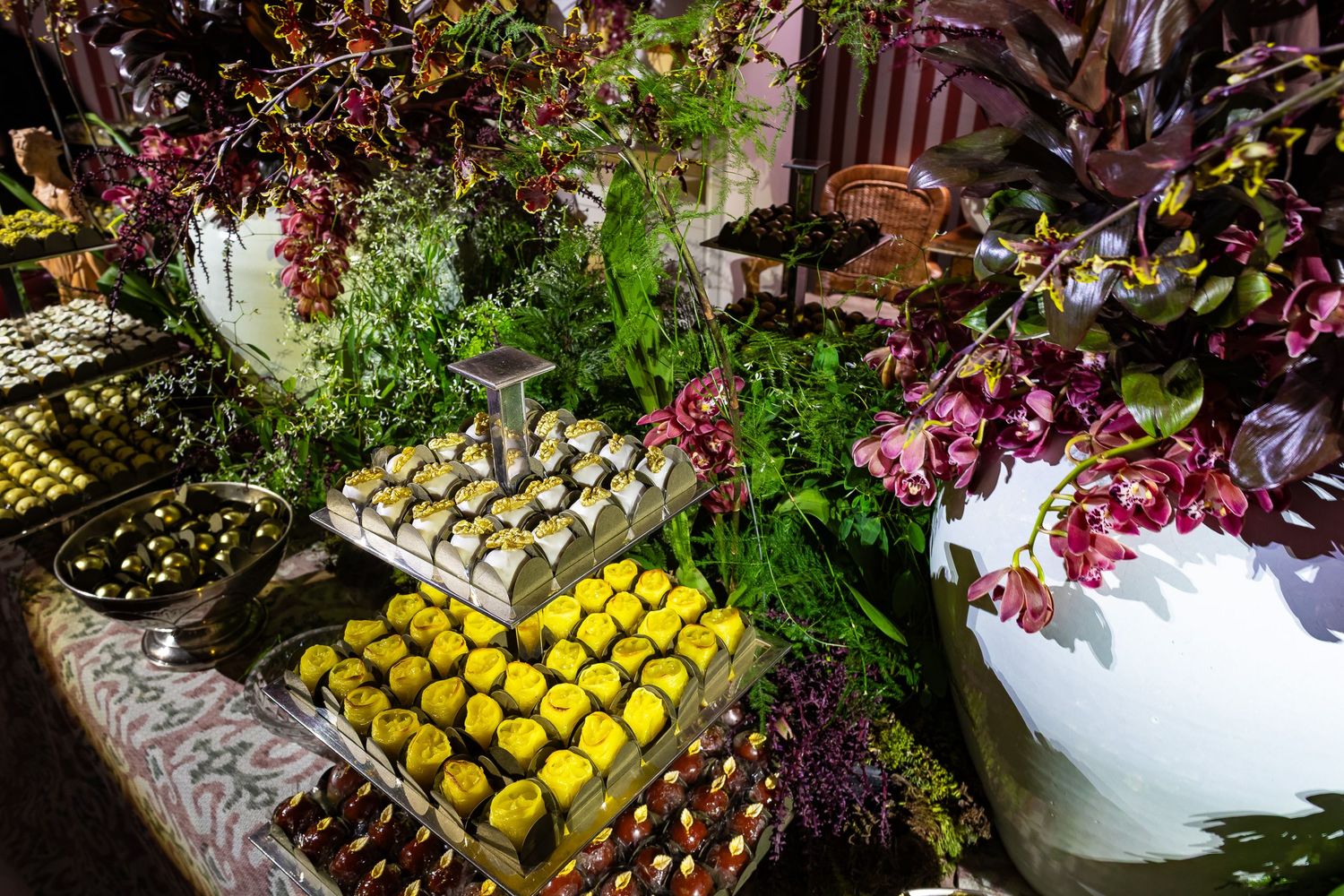 Vibrant display of fresh lemons and purple flowers arranged on rustic wooden surfaces at a farmers market or produce stand.