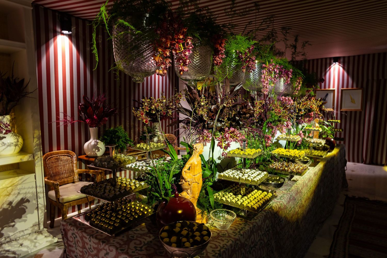 Illuminated garden path with striped awnings features lush greenery and decorative elements at night.