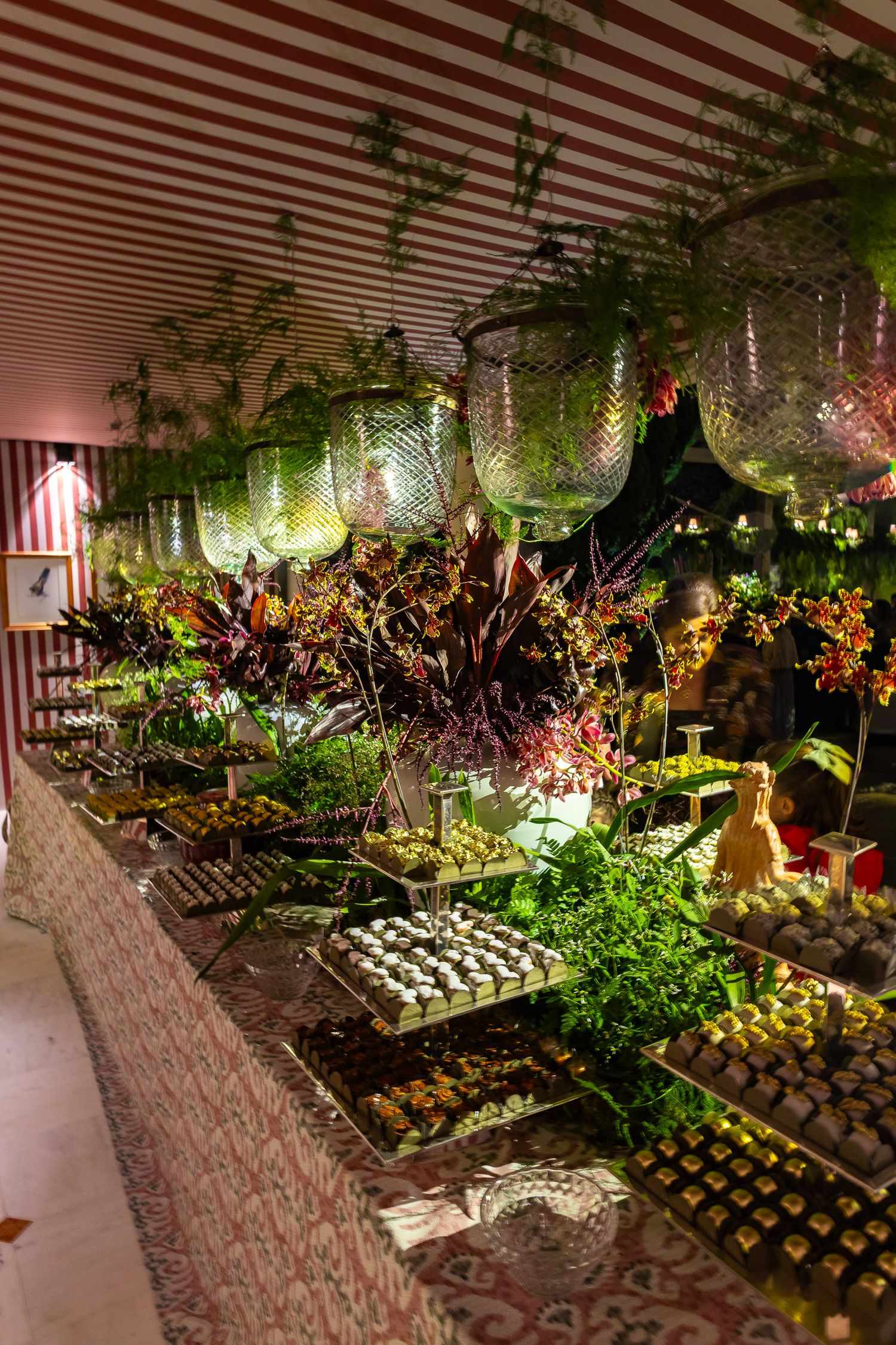 Illuminated garden display with wine bottles and lush greenery under warm lighting creates a magical nighttime atmosphere.